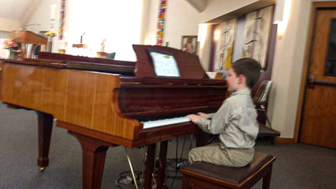 student Liam playing a grande piano